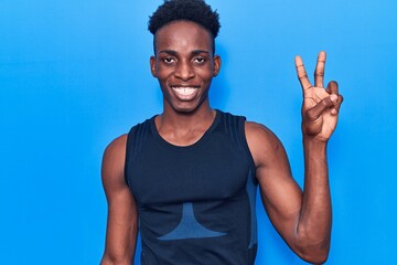 Young african american man wearing sportswear smiling with happy face winking at the camera doing victory sign. number two.