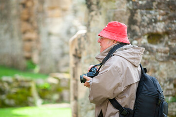 An elderly man with a camera in ancient ruins