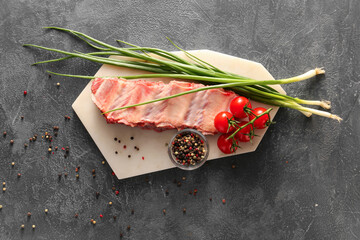 Raw beef short ribs with vegetables and spices on dark background