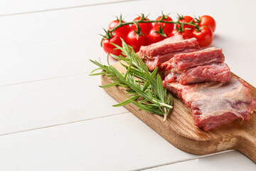 Raw beef short ribs with tomatoes and herbs on table