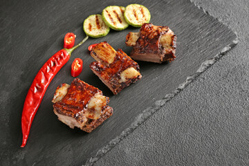 Tasty beef short ribs with vegetables on slate plate