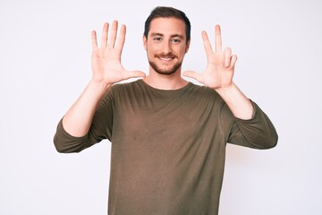 Naklejka premium Young handsome man wearing casual clothes showing and pointing up with fingers number eight while smiling confident and happy.