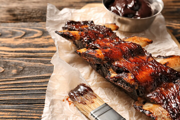 Tasty beef short ribs with sauce on table, closeup