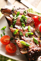 Tasty beef short ribs with vegetables on plate, closeup