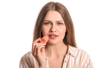 Beautiful young woman with lip balm on white background