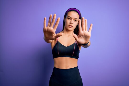 Young beautiful sporty girl doing sport wearing sportswear over isolated purple background doing stop gesture with hands palms, angry and frustration expression