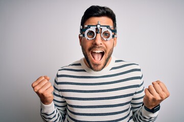 Naklejka premium Young handsome man with beard wearing optometry glasses over isolated white background celebrating surprised and amazed for success with arms raised and open eyes. Winner concept.