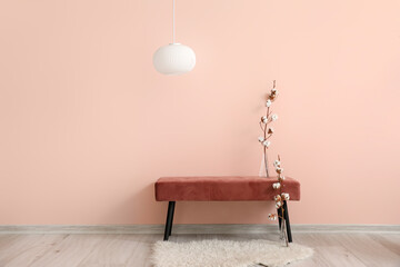 Stylish bench with cotton flowers near color wall in room