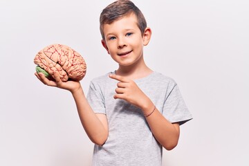 Cute blond kid holding brain smiling happy pointing with hand and finger