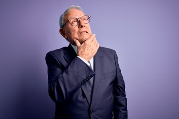 Obraz premium Grey haired senior business man wearing glasses and elegant suit and tie over purple background Thinking worried about a question, concerned and nervous with hand on chin