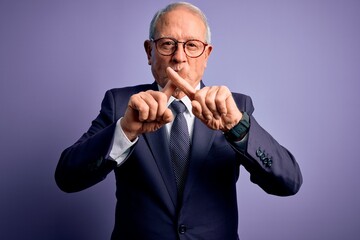 Grey haired senior business man wearing glasses and elegant suit and tie over purple background Rejection expression crossing fingers doing negative sign