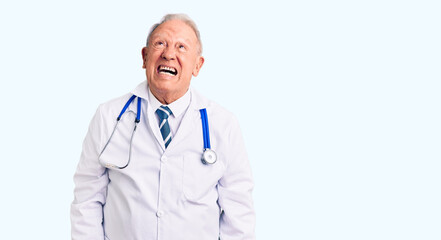 Fototapeta premium Senior handsome grey-haired man wearing doctor coat and stethoscope angry and mad screaming frustrated and furious, shouting with anger. rage and aggressive concept.