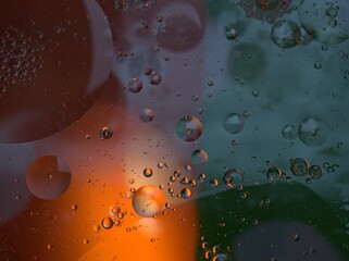 Closeup golden yellow bubbles oil in water with green orange light , blurred abstract background, macro image ,droplets for card design