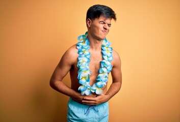 Young handsome tourist man on vacation wearing swimwear and hawaiian lei flowers with hand on...