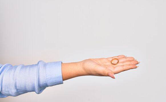 Hand of caucasian young woman holding golden marriage ring over isolated white background