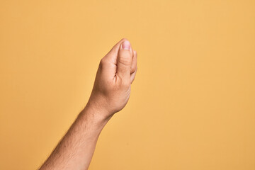 Naklejka premium Hand of caucasian young man showing fingers over isolated yellow background holding blank space with thumb finger, business and advertising