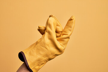 Hand of caucasian young man with gardener glove over isolated yellow background snapping fingers for success, easy and click symbol gesture with hand