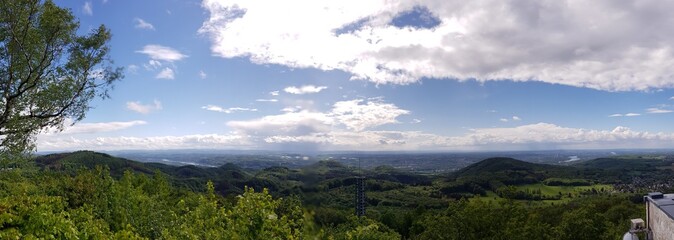 Aerial panoramic view of a green forest under blue sky and white clouds