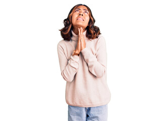 Young beautiful mixed race woman wearing winter turtleneck sweater begging and praying with hands together with hope expression on face very emotional and worried. begging.