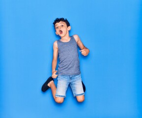 Adorable kid wearing casual clothes jumping over isolated blue background