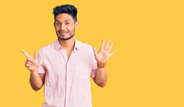 Handsome latin american young man wearing casual summer shirt showing and pointing up with fingers number seven while smiling confident and happy.