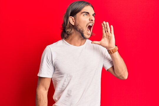 Young handsome man wearing casual clothes shouting and screaming loud to side with hand on mouth. communication concept.