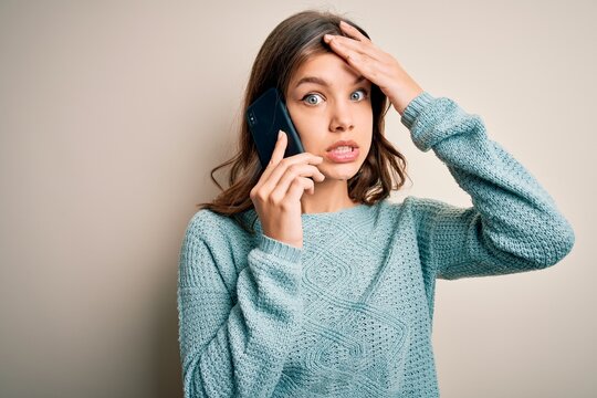 Young blonde girl having a conversation talking on smartphone over isolated background stressed with hand on head, shocked with shame and surprise face, angry and frustrated. Fear and upset.