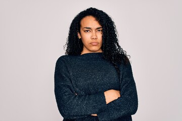 Young african american curly woman wearing casual sweater standing over white background skeptic...