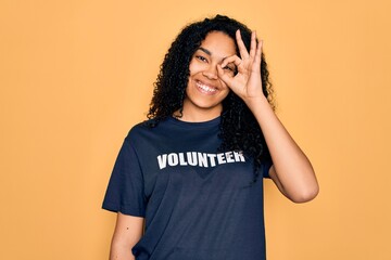 Young african american curly woman doing volunteering wearing volunteer t-shirt with happy face...