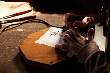 young man carving figures on wood