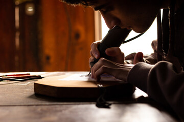 young man carving figures on wood