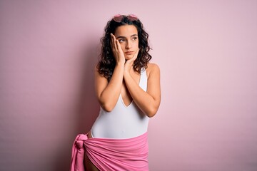 Beautiful woman with curly hair on vacation wearing white swimsuit over pink background Tired hands covering face, depression and sadness, upset and irritated for problem