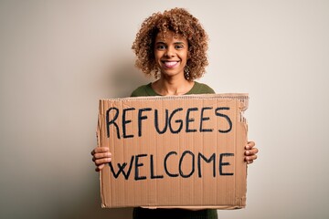 African american woman asking for immigration holding banner with wlecome refugees message with a happy face standing and smiling with a confident smile showing teeth - obrazy, fototapety, plakaty