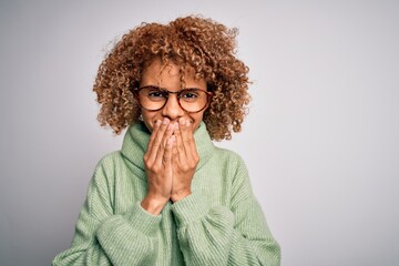 Fototapeta na wymiar Young beautiful african american woman wearing turtleneck sweater and glasses laughing and embarrassed giggle covering mouth with hands, gossip and scandal concept