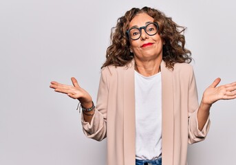 Middle age beautiful businesswoman wearing glasses standing over isolated white background clueless...