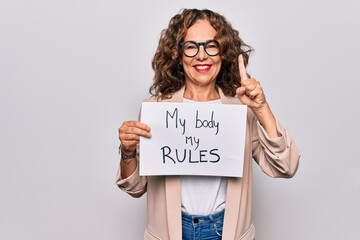 Middle age beautiful woman asking for women rights holding paper with feminist message smiling with...