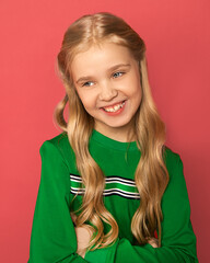 A beautiful blonde girl of 8-10 years old with blue eyes, hair arranged in curls in bright clothes...