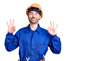 Young hispanic man wearing worker uniform relaxed and smiling with eyes closed doing meditation gesture with fingers. yoga concept.