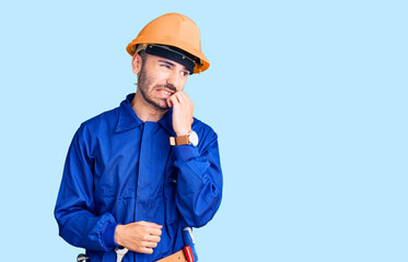 Young hispanic man wearing worker uniform looking stressed and nervous with hands on mouth biting...