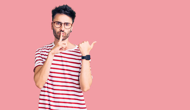 Young hispanic man wearing casual clothes asking to be quiet with finger on lips pointing with hand to the side. silence and secret concept.
