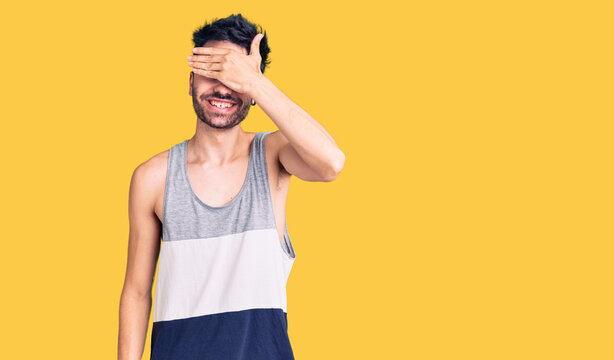 Young hispanic man wearing casual clothes smiling and laughing with hand on face covering eyes for surprise. blind concept.