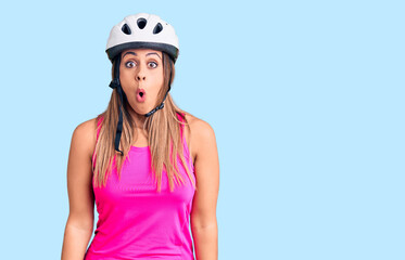 Young beautiful woman wearing bike helmet scared and amazed with open mouth for surprise, disbelief face