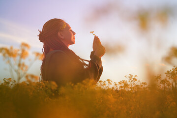 red-haired girl in a field of diverse flowers. the concept of freedom, relaxation, enjoyment of the...
