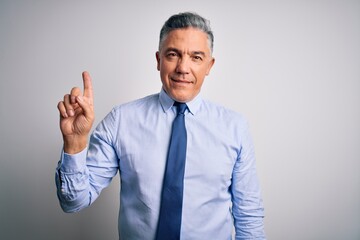 Middle age handsome grey-haired business man wearing elegant shirt and tie pointing finger up with successful idea. Exited and happy. Number one.