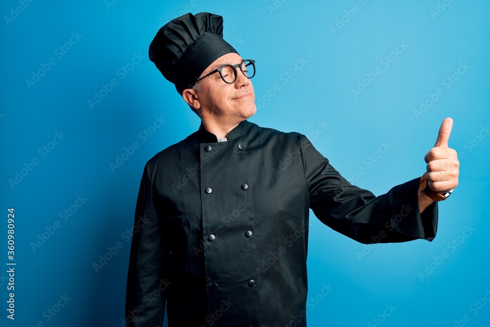 Sticker Middle age handsome grey-haired chef man wearing cooker uniform and hat Looking proud, smiling doing thumbs up gesture to the side