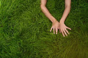 female hands lie in different positions on the green grass. the concept of the unification of nature and man, natural cosmetics and natural beauty