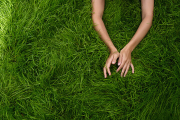 female hands lie in different positions on the green grass. the concept of the unification of nature and man, natural cosmetics and natural beauty