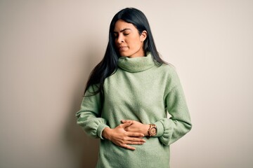 Young beautiful hispanic woman wearing green winter sweater over isolated background with hand on...