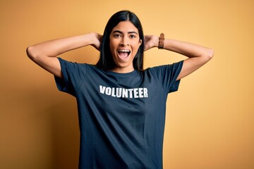 Young beautiful hispanic woman wearing volunteer t-shirt as social charity moral Crazy and scared with hands on head, afraid and surprised of shock with open mouth