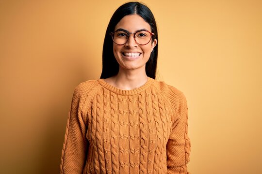 Young beautiful hispanic woman wearing glasses over yellow isolated background with a happy and cool smile on face. Lucky person.